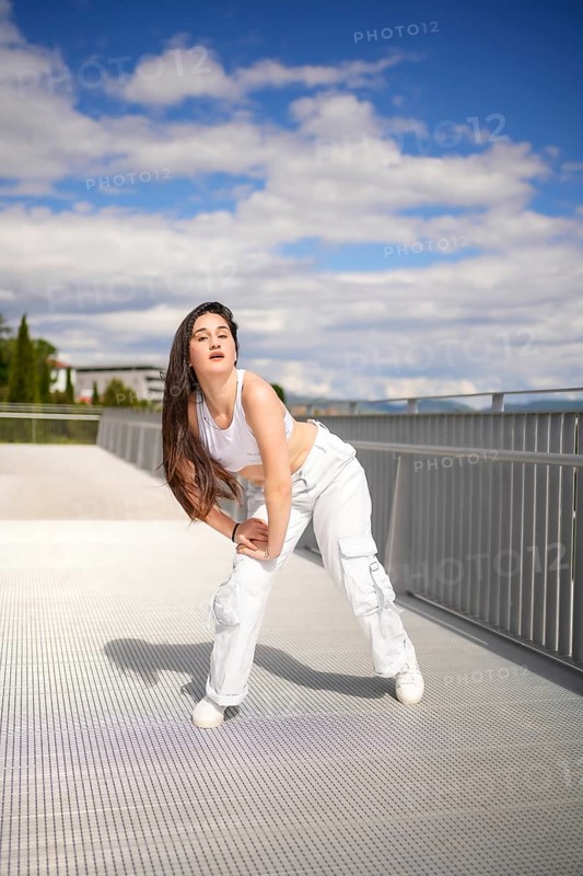 Vertical full length photo of a caucasian young female artist performing urban dance on a bridge