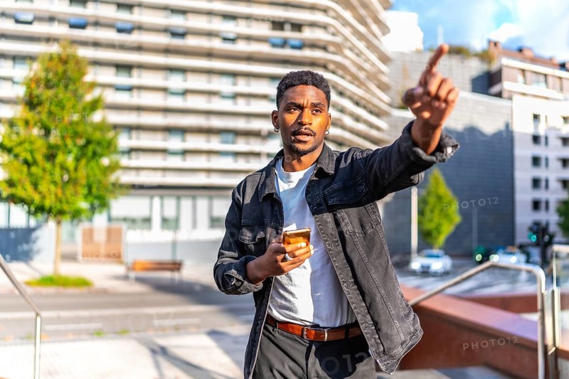 African man pointing to a direction using gps mobile app in the city