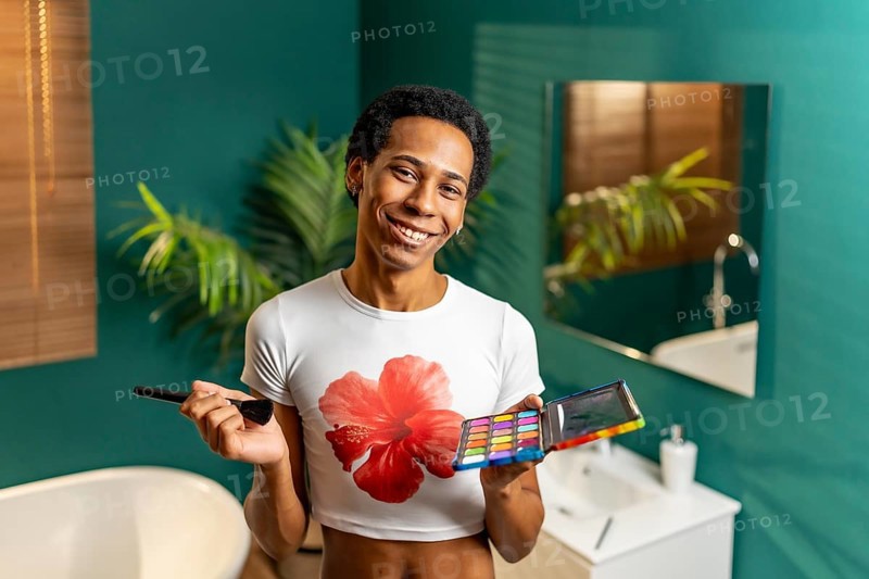 Portrait of a latin young gay smiling man making up at home