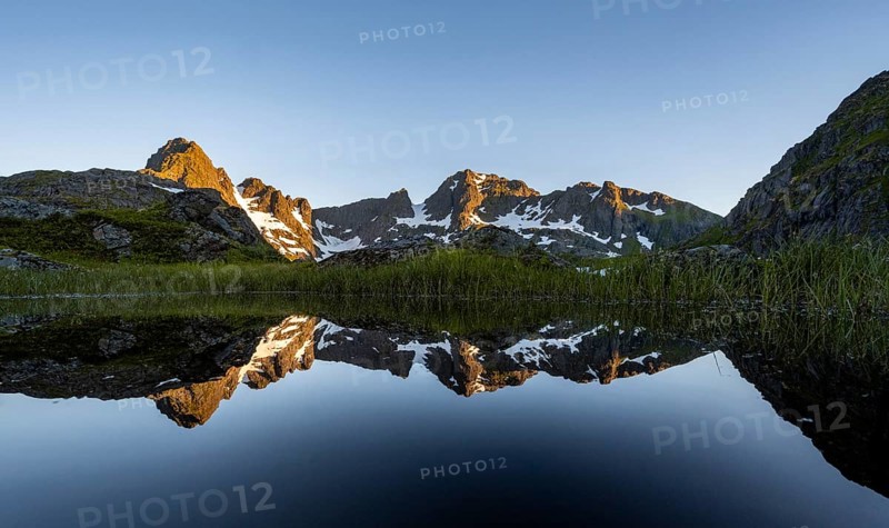 Rocky mountain peaks reflected in a small pond, mountain landscape with alpenglow at sunrise, at the Trollfjord Hytta, at the Trollfjord, Lofoten and Vesterålen, Nordland, Norway, Europe