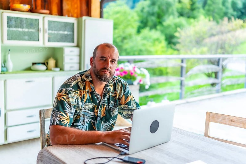 Digital nomad working on laptop in a mountain chalet, enjoying the freedom of remote work and a nomadic lifestyle