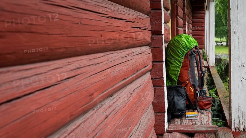 A pilgrim's rucksack standing against a wooden shed painted falun red, medieval church, pole, Norway, Europe