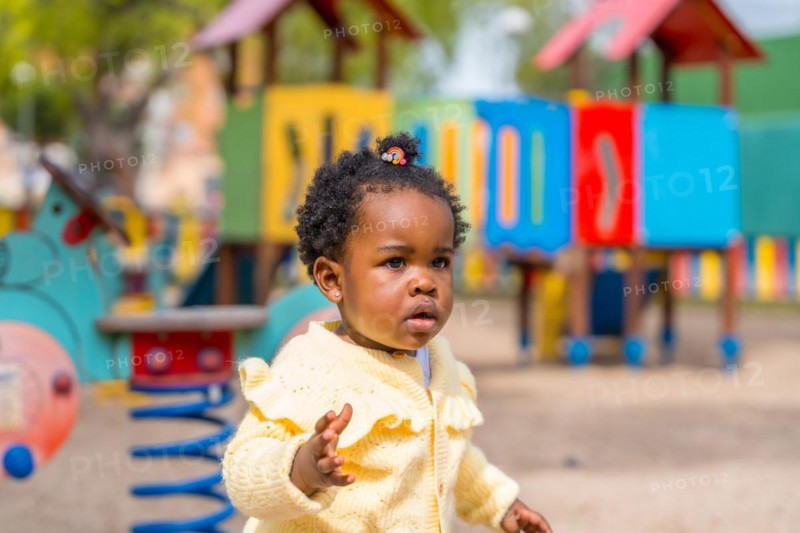 A little african girl playing on playground under the sun