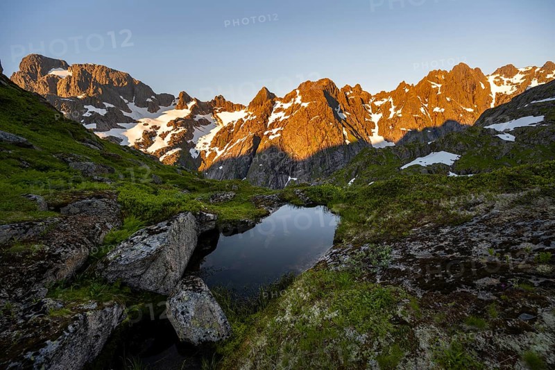 Rocky mountain peaks with reflection, small pond in moor landscape at Trollfjord Hytta, mountain landscape with alpenglow at sunrise, at Trollfjord, Lofoten and Vesterålen, Nordland, Norway, Europe