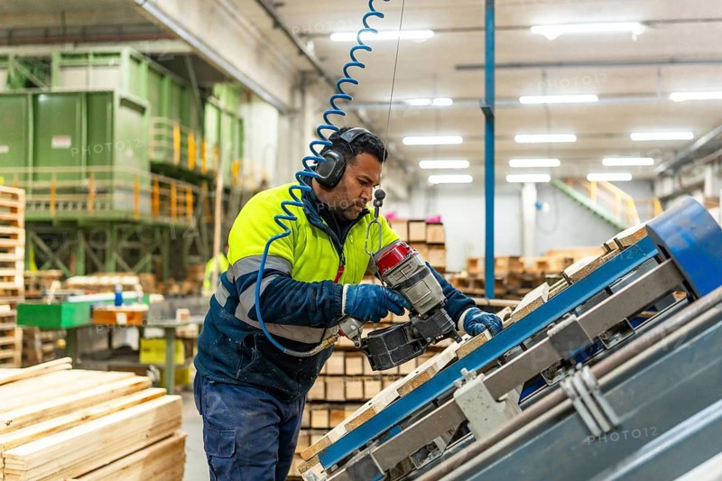 Side view three quarter length photo of a caucasian man worker arranging pallets to reuse it in a recycling plant factory