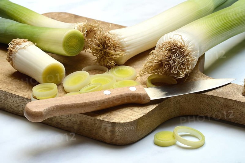 Leek, leek sticks and leek rings on a chopping board with a knife