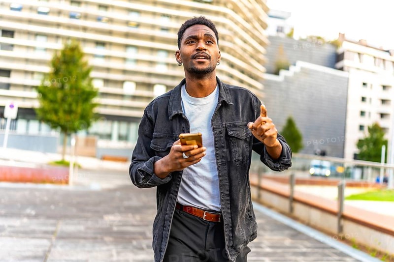 African man walking along the city using gps app to find a direction
