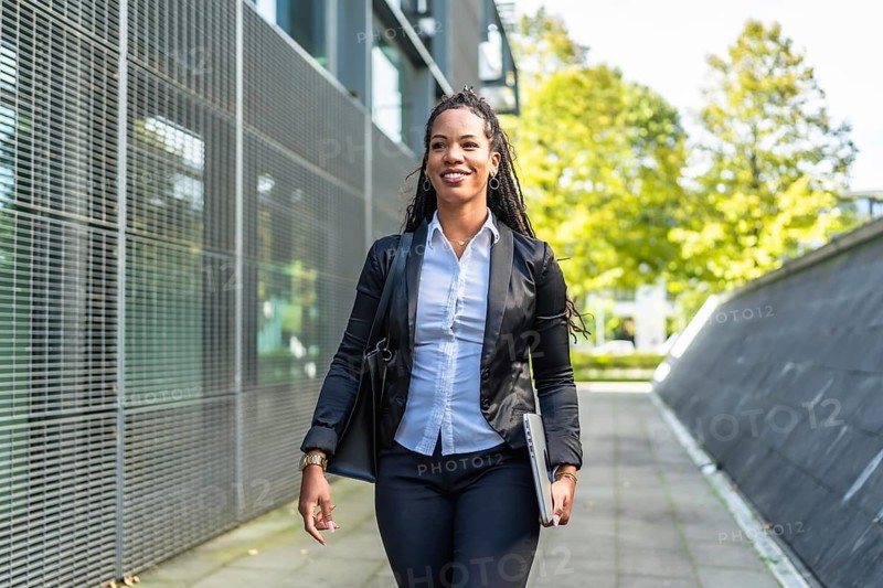 Real estate agent latin woman walking outside building holding laptop