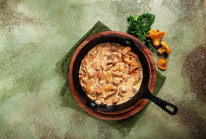 Fried chanterelle mushrooms, in cream sauce, in a cast-iron pan, homemade, no people