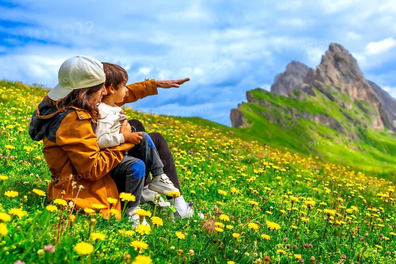 Mother and child admiring the landscape in the seceda mountains in the dolomites, italy, during a summer day