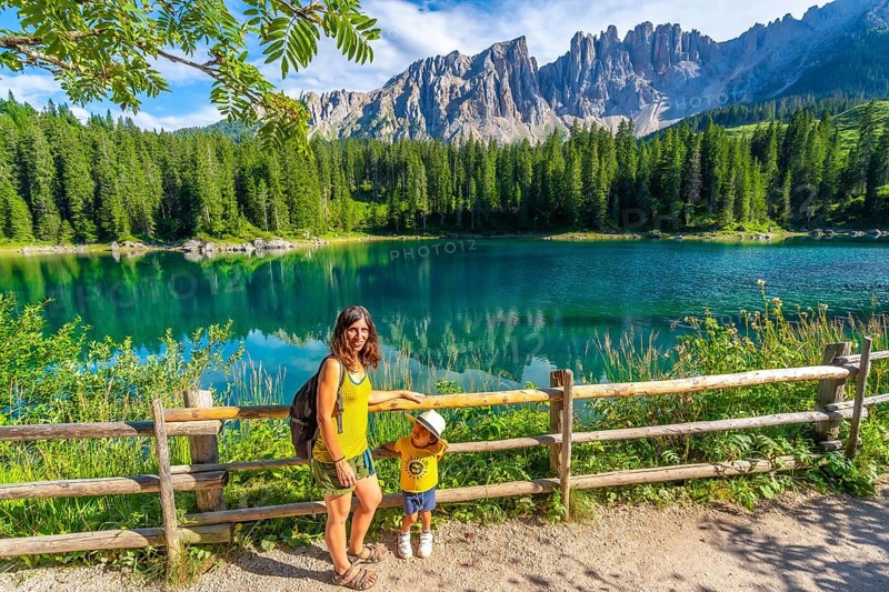 Mother and child enjoying summer holidays at the magnificent lake carezza with the latemar massif in the background, dolomites, italy