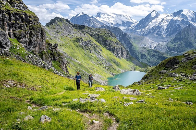 Hiker and mountain lake Lac de Louvie with glaciated summit of the Grand Combin, Val de Bagnes, Valais, Switzerland, Europe