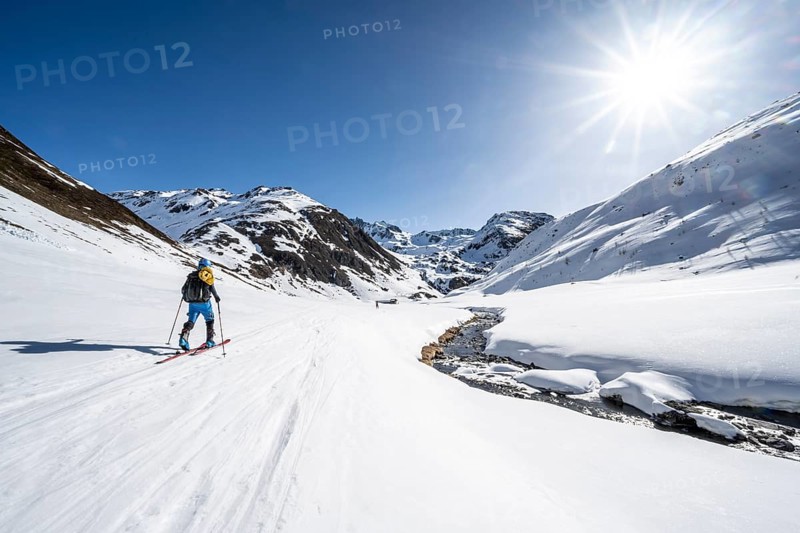 Ski tourer in the snow by a mountain stream in the Funtauna Valley, Sonnenstern, Graubünden Haute Route, Albula Alps, Rhaetian Alps, Graubünden, Switzerland, Europe