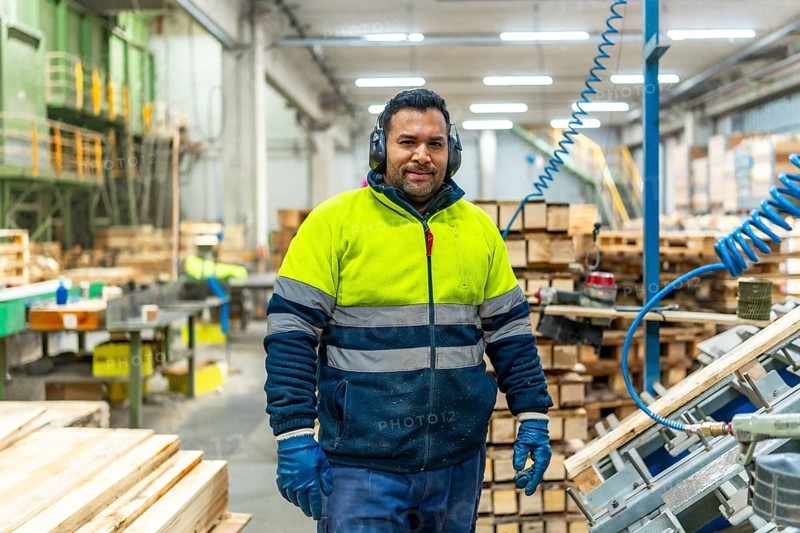 Man carpenter with protective work gear standing in a recycling plant arranging pallets to reuse