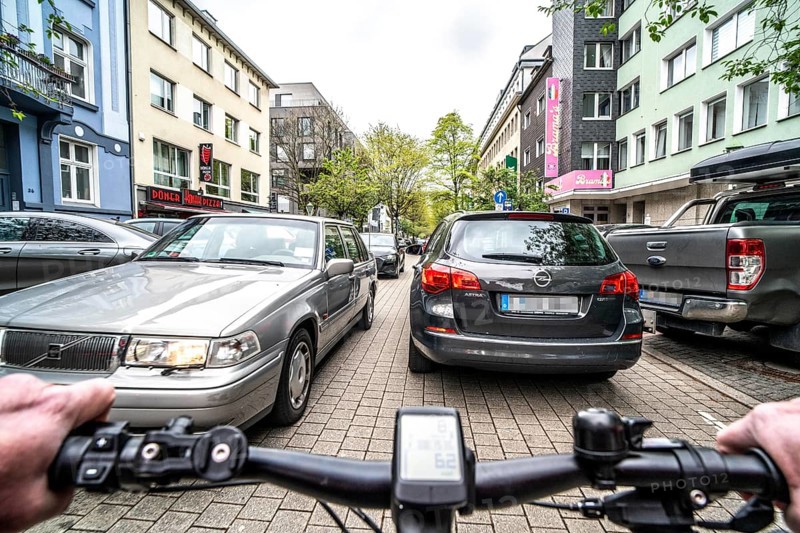 Cycling in the city, inner-city street, cycle lane, bicycles have priority, two-lane traffic with parked cars on both sides, cyclists' perspective, Essen, North Rhine-Westphalia, Germany, Europe