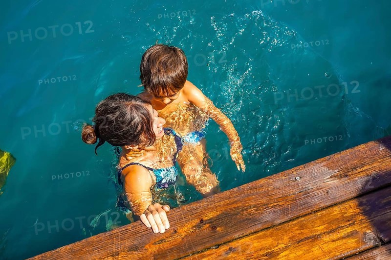 Mother and son having fun swimming in the turquoise water of lake bled, a popular tourist destination in the julian alps