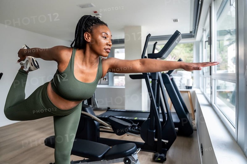 Manager stretching legs in hotel fitness room during business trip, maintaining healthy lifestyle while traveling