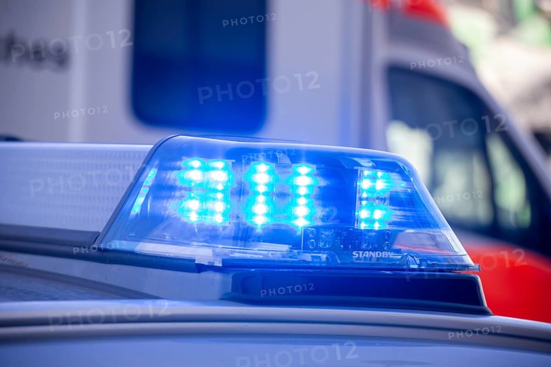 Close-up of flashing blue lights during a police operation with an ambulance in the background