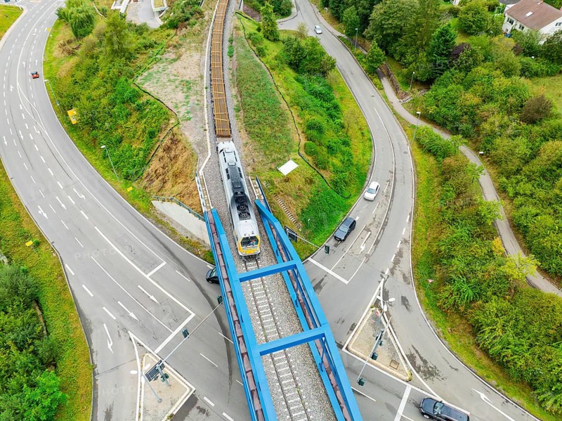 Railway train crosses a bridge with roads and vehicles, track construction, rail delivery for Hermann Hessebahn, Calw, Black Forest, Germany, Europe
