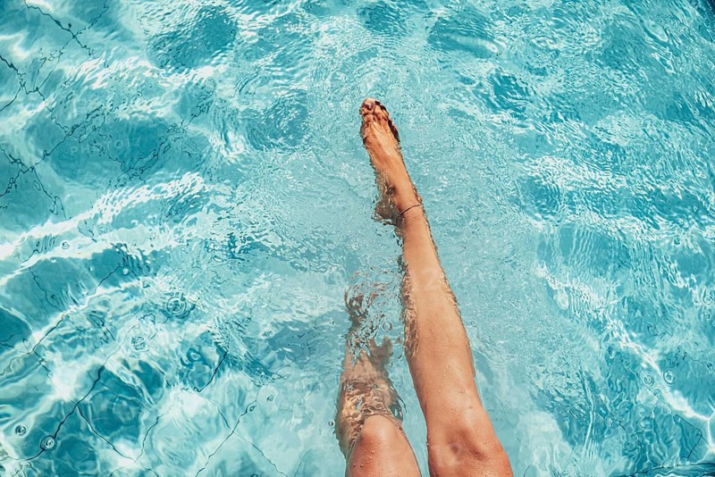 Beautiful legs of a woman splashing in a turquoise-coloured pool