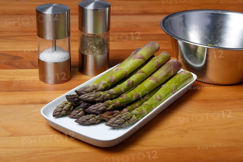 South German cuisine, vegetables, vegetarian, preparation of green asparagus with rhubarb vinaigrette and potato gratin, healthy, raw asparagus on serving platter, rhubarb sliced in bowl behind, salt, pepper mill, traditional cuisine reinterpreted, food photography, studio, Germany, Europe