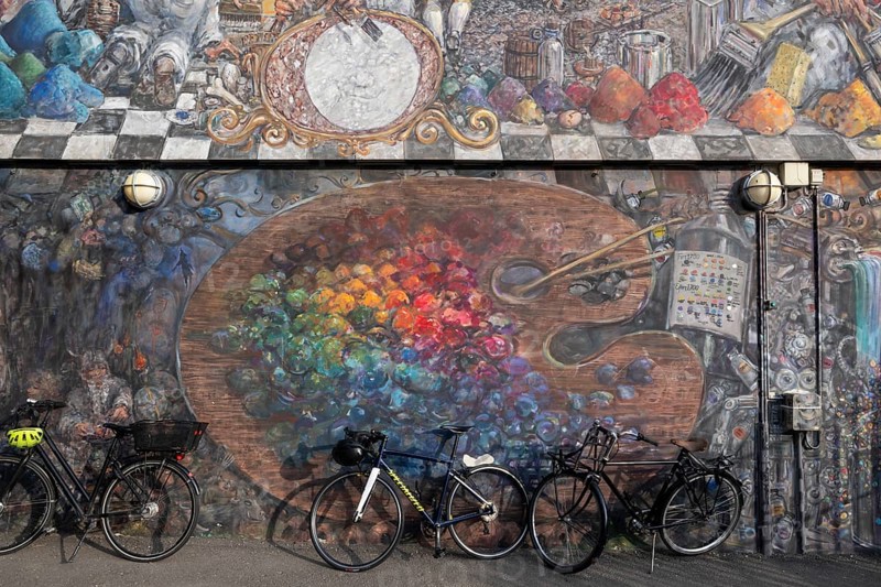 Bicycles in front of a house wall with large-format graffiti of a colour palette, Sølvgades Skole, Copenhagen, Denmark, Europe