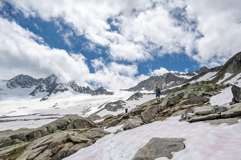 Mountaineer on a hiking trail between snow, descent from the summit of Schönbichler Horn, view of snow-covered and glaciated mountain landscape with summit Großer Möseler, Berliner Höhenweg, Zillertal Alps, Tyrol, Austria, Europe
