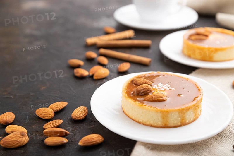 Sweet tartlets with almonds and caramel cream with cup of coffee on a black concrete background and linen textile. Side view, close up, selective focus