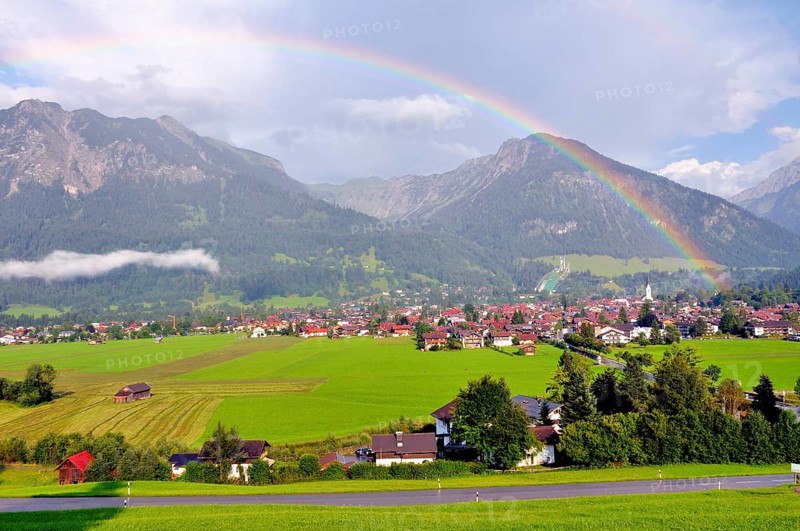 View over Oberstdorf with rainbow, behind it the Schattenberg with Schattenbergschanze, Oberallgäu, Bavaria, Germany, Europe