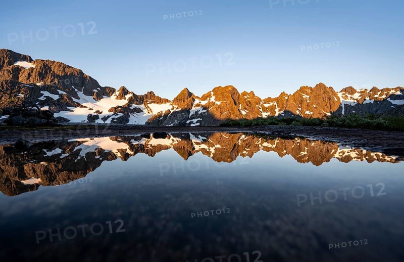 Rocky mountain peaks reflected in a small pond, mountain landscape with alpenglow at sunrise, at the Trollfjord Hytta, at the Trollfjord, Lofoten and Vesterålen, Nordland, Norway, Europe