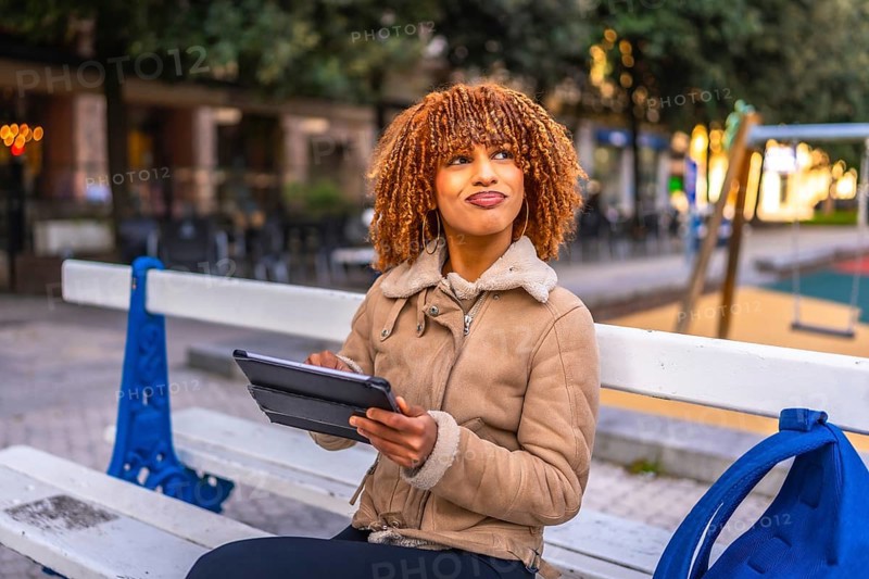 Creative beauty young latin woman sitting on a bench using digital tablet to work in the city