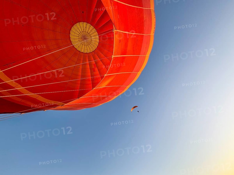 Hot air balloon ride, Paraglider with motor passes the hot air balloon. Background blue sky. Alice Springs, Northern Territory, Australia, Oceania