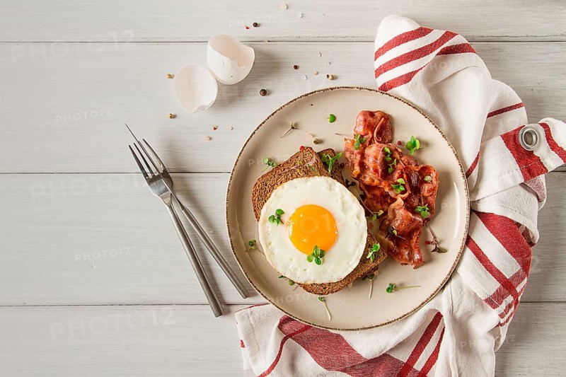 Breakfast, fried egg with bacon, micro-green, on a light background, no people, selective focus