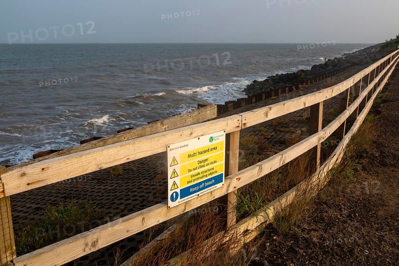 Environment Agency warning danger sign above rock armour, East Lane, Bawdsey, Suffolk, England, UK