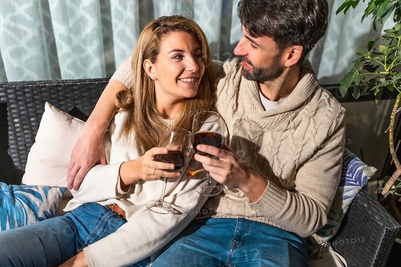 Romantic couple toasting with red wine, enjoying a cozy moment together on a comfortable sofa