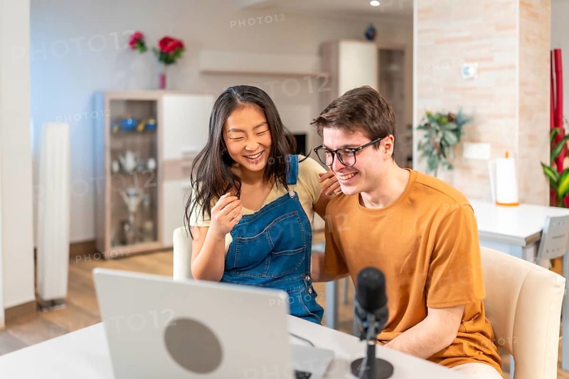 Asian woman and caucasian man smiling while engaging in a fun activity at home, showcasing a joyful and relaxed atmosphere