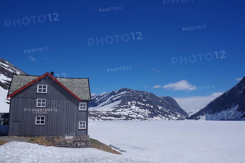 Mountain hut in a snow-covered late winter landscape, surrounded by mountains and a frozen lake, under a clear blue sky, Langevatn, Geiranger, Fjell, Norway, Europe