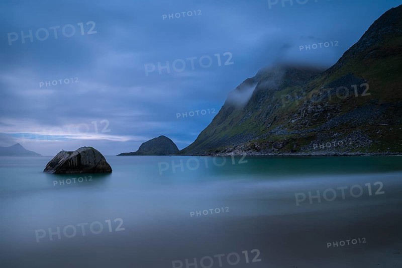 Landscape on the beach at Haukland. The mountains Veggen and Mannen on the right. The sky is cloudy. The sea is blurred due to the long exposure. Early summer, at night. Haukland Beach, Haukland, Vestvagoya, Lofoten, Norway, Europe