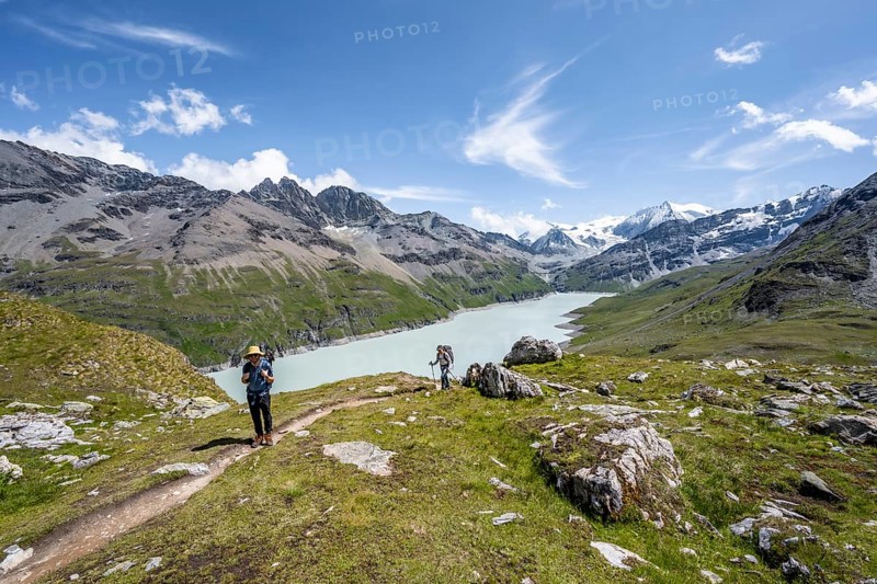 Two mountaineers on a hiking trail at a blue mountain lake, reservoir Lac des Dix, behind mountain peak Mont Blanc de Cheilon, Hérménence, Valais Alps, Valais, Switzerland, Europe