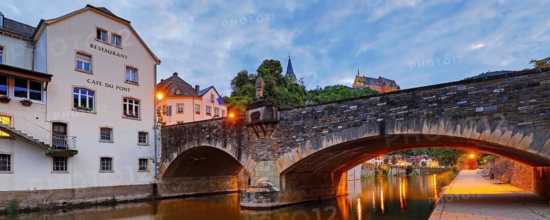 Town view of Vianden with the old stone bridge over the river Our and the castle in the evening, Grand Duchy of Luxembourg