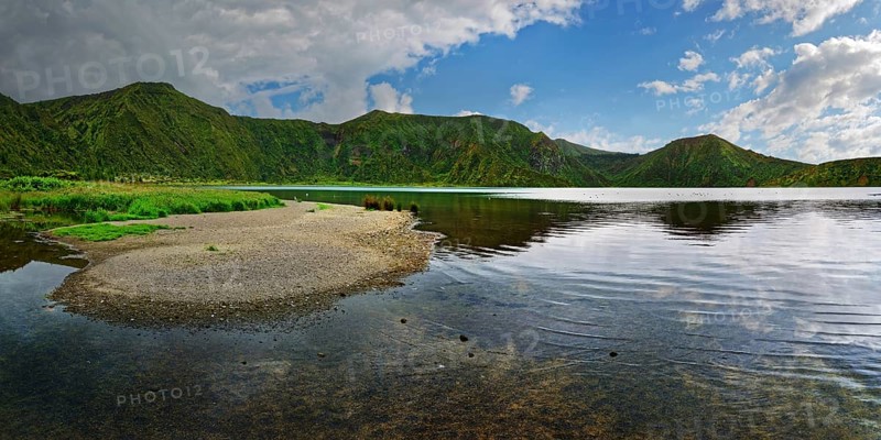 Calm lake surrounded by green mountains under a partly cloudy sky, crater lake Lagoa do Fogo, Caldeiras, Sao Miguel Island, Azores, Portugal, Europe