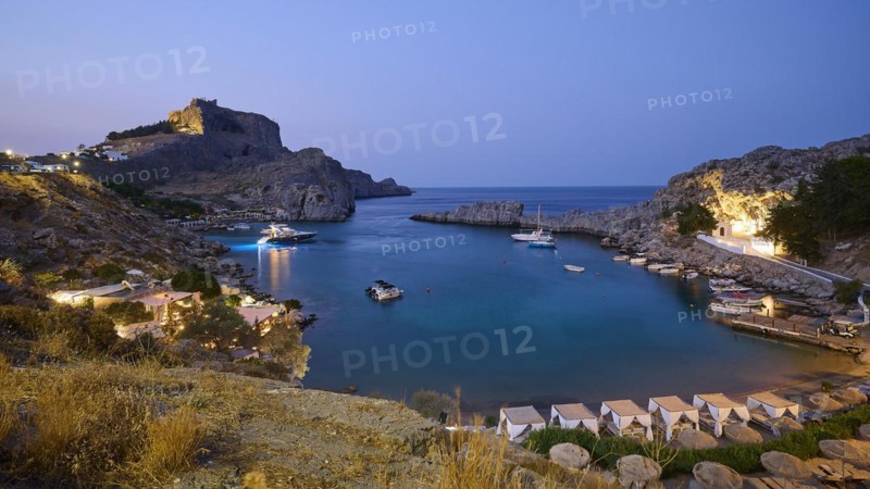St Paul's Bay in the evening light, view of an illuminated bay with boats and calm water at dusk, Acropolis of Lindos, Lindos, Rhodes, Dodecanese, Greek Islands, Greece, Europe