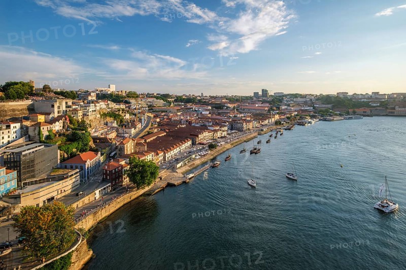 View of Vila Nova de Gaia city and Douro river with tourist boats on sunset. Porto, Portugal, Europe