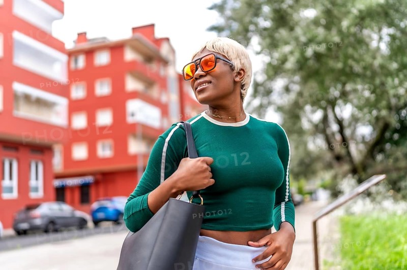 Cool african blonde woman smiling wearing casual clothes and sunglasses in the street