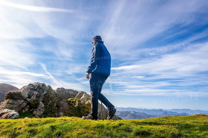 Male hiker using a walking stick while enjoying a sunny day on the summit of mount penas de aya or aiako harria, in oiartzun, basque country, spain