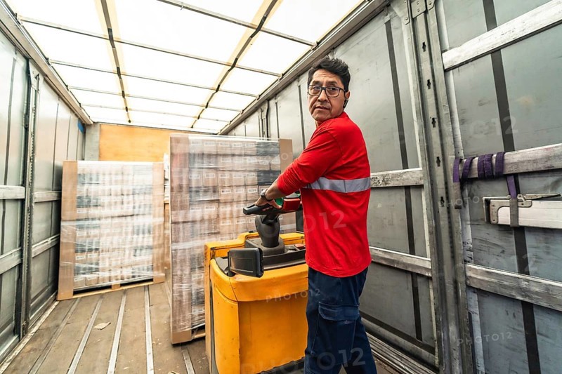 Rear view of a concentrated latin man worker loading a delivery truck in distribution warehouse