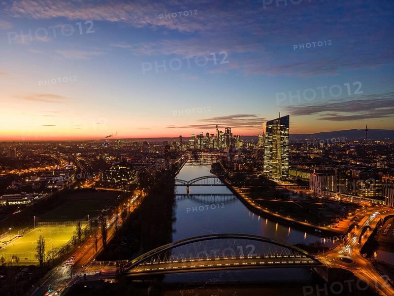 The lights in the offices of the European Central Bank (ECB) and in the skyscrapers of Frankfurt's banking skyline glow in the evening shortly after sunset. (Aerial view with a drone), Frankfurt am Main, Osthafen, Hesse, Germany, Europe