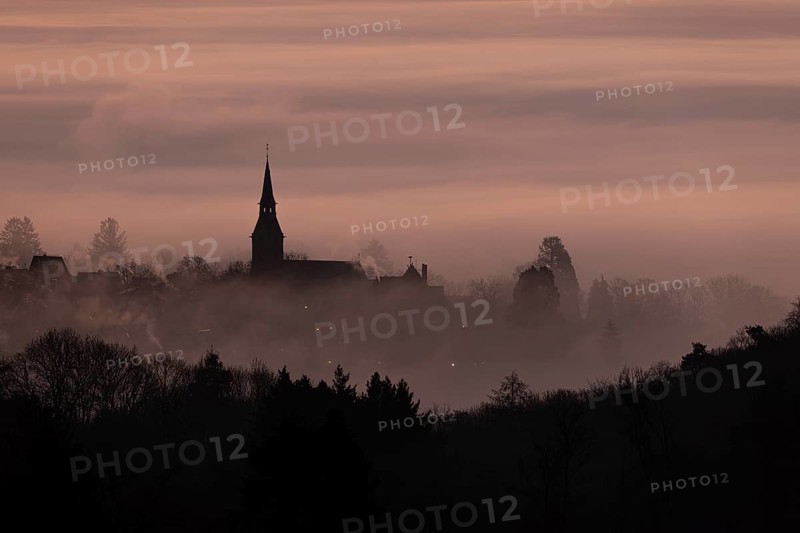 Wisps of mist drift into the town of Kronberg im Taunus in the morning shortly in front of sunrise. Only the spire of St Peter and Paul's Church stands out. Kronberg, Malerblick, Hesse, Germany, Europe