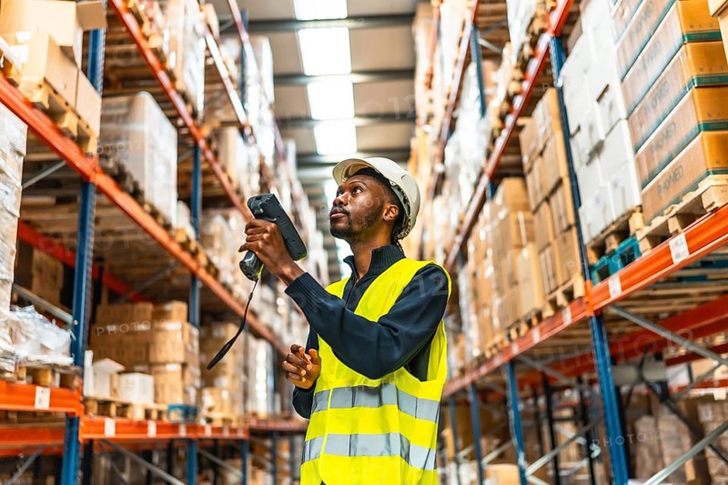 African man using scanner to read the barcodes and check the packages in a warehouse