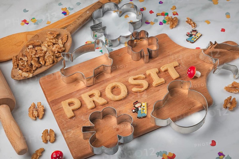 Cheers lettering made from biscuit dough on a wooden board, baking accessories, cookie cutters